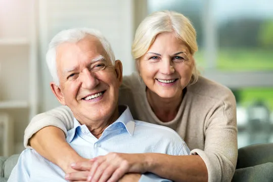 Smiling older couple embracing, representing the positive impact of dental implants on their lives