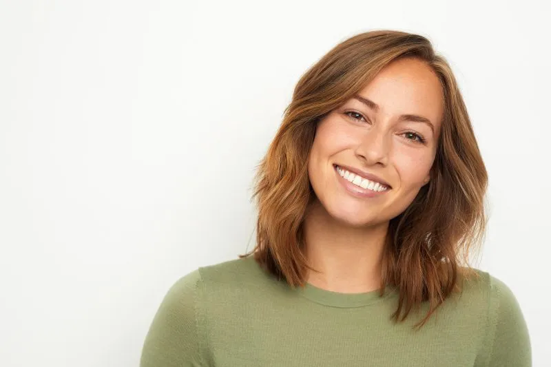 Smiling young woman with straight teeth, representing the benefits of dental implants